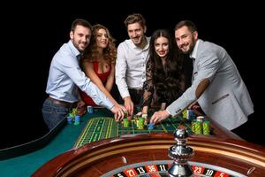 groep van jong mensen achter roulette tafel in een casino foto