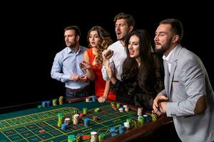 groep van jong mensen achter roulette tafel in een casino foto