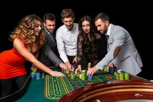 groep van jong mensen achter roulette tafel in een casino foto