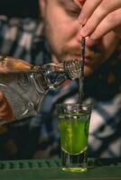 geschoold barman voorbereidingen treffen gelaagde drinken groen Mexicaans Aan bar teller foto