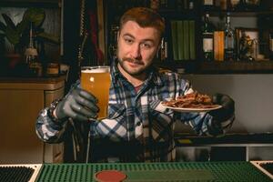 vriendelijk gebaard barman aanbieden glas van bier met snacks in kroeg foto