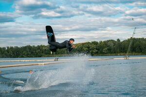 zelfverzekerd mannetje wakeboarder jumping over- water oppervlakte Aan meer Aan zomer dag foto