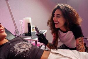 vrolijk jong vrouw tatoeëren artiest chatten met cliënt in tatoeëren salon foto