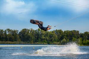 zelfverzekerd wakeboard rijder gesleept Aan kabel tonen trucs in Open water foto