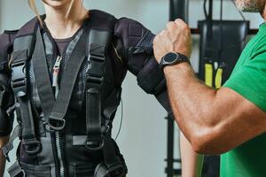 gespierd geschiktheid instructeur is zetten Aan een ems pak voor atletisch vrouw. opleiding in een Sportschool door een methode naar toenemen energie. foto