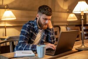 jong professioneel surfing de internet Aan zijn laptop in een cafe foto