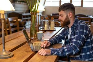 jong professioneel surfing de internet Aan zijn laptop in een cafe foto