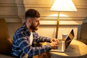 jong professioneel surfing de internet Aan zijn laptop in een cafe foto