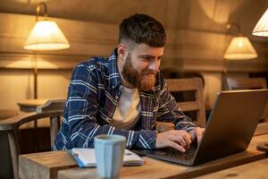 jong professioneel surfing de internet Aan zijn laptop in een cafe foto