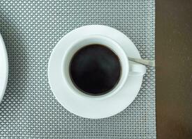zwart koffie in wit keramisch kop Aan tafel foto
