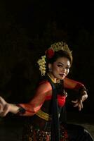 een Indonesisch danser poseren met haar mooi en mooi handen terwijl vervelend bedenken Bij nacht foto