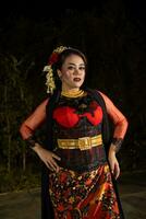 een Indonesisch danser in een goud en rood kostuum staat heel sierlijk foto