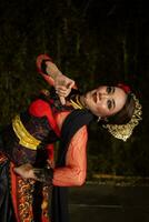 een Javaans danser dansen in voorkant van de publiek met een behendig lichaam in een zwart kostuum foto