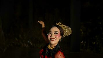 een Indonesisch danser met gelaats uitdrukkingen dat straalt uit schoonheid en geluk dansen en boeit de publiek foto