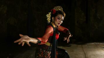 een Javaans danser gekleed in traditioneel rood kleren betoverd de publiek met haar bevallig bewegingen dat blended met de melodie foto