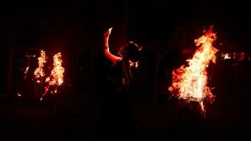 de silhouet van een vrouw danser Holding sieraden in de donker van nacht is lit door de licht van een brandend brand foto