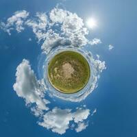 groene kleine planeet in blauwe lucht met prachtige wolken. transformatie van bolvormig panorama 360 graden. sferische abstracte luchtfoto. kromming van de ruimte. foto