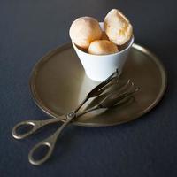 heerlijk bijtdessert gevuld met room. gezet in een witte kom op een antiek bronzen dienblad. mooie bronzen serveertangen. gastronomie foto