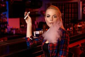 jong mooi vrouw rook een elektronisch sigaret Bij de vapen bar foto