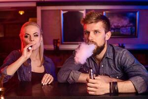 een Mens en vrouw roken elektronisch sigaret in een vapen bar. foto