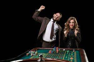 Mens en vrouw spelen Bij roulette tafel in casino foto