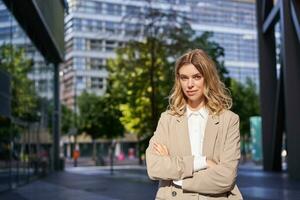 geslaagd werken vrouw, kantoor manager in pak, kruis armen Aan borst, op zoek met vertrouwen foto