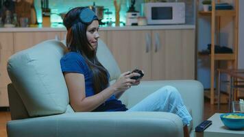 gamer vrouw spelen video spellen Aan troosten gebruik makend van controleur en joysticks zittend Aan bankstel in voorkant van TV. opgewonden vastbesloten persoon ontspannende gaming met draadloze controleur hebben pret winnend foto