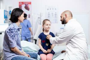 kinderarts controle Gezondheid van kind gebruik makend van stethoscoop in ziekenhuis kantoor gedurende overleg. gezondheidszorg arts specialist in geneeskunde het verstrekken van Gezondheid zorg Diensten behandeling inspectie. foto