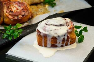 gekookt gebakken zoet cinnabon met room in bakken papier . foto