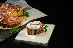 gekookt gebakken zoet cinnabon met room in bakken papier . foto