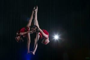 circus actrice acrobaat prestatie. twee meisjes uitvoeren acrobatisch elementen in de lucht ring. foto