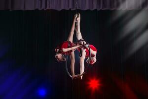 circus actrice acrobaat prestatie. twee meisjes uitvoeren acrobatisch elementen in de lucht ring. foto