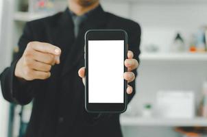 zakenman die een lege witte smartphone met touchscreen houdt. gebruikt om tekst of informatie te plaatsen om nieuws te adverteren of producten online te verkopen. concept marketing bedrijf foto
