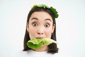 dichtbij omhoog portret van glimlachen Aziatisch vrouw aan het eten sla, liefdes kool, vegetarisch geniet rauw biologisch voedsel, wit achtergrond foto