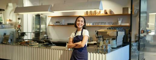 portret van glimlachen Aziatisch ondernemer, onafhankelijk koffie winkel baasje, vervelend schort, werken in cafe, vervelend schort foto