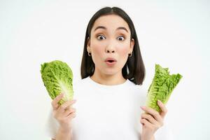 gezond eetpatroon en biologisch voedsel. glimlachen Aziatisch vrouw tonen kool, aan het eten sla, reiniging haar lichaam, Aan ontgiften, wit achtergrond foto
