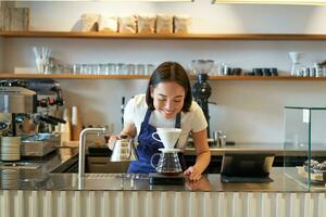 glimlachen Aziatisch meisje barista, werken in cafe, brouwen koffie v60, voorbereidingen treffen bestellen achter teller foto