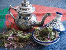 een thee pot en een kom van droog kruiden foto