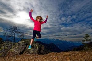 meisje springt van rotsen in de bergen tijdens een training foto