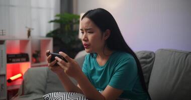 portret van jong Aziatisch vrouw echt spelen een online spel gefrustreerd met verlies of mislukking zittend Aan sofa in leven kamer Bij thuis.gamer levensstijl concept, gamer levensstijl concept. foto