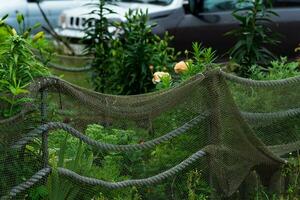 landschap ontwerp in een kust dorp, een bloem bed is omheind met een oud visvangst netto foto