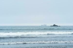 landschap met een zee rots en een het zeilen schip in de afstand foto