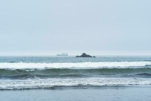landschap met een zee rots en een het zeilen schip in de afstand foto