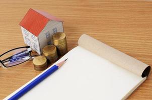 hypotheekleningen concept met potlood en notitieblok met papieren huis en munten stapel foto