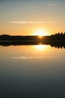 zonsondergang met reflectie Aan een Zweeds meer in klein en. romantisch avond humeur. foto