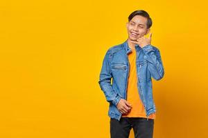 aantrekkelijke aziatische man die roepnaam maakt en zijwaarts kijkt op gele achtergrond