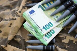 bundels van euro rekeningen en een machine geweer riem Aan de camouflage uniform van een oekraïens soldaat. concept van oorlog financiering, steekpenning of bijdrage foto