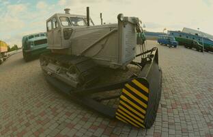 foto van een grijs bulldozer tussen de spoorweg treinen. sterk vervorming van de vissenoog lens