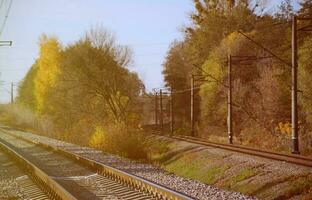 herfst industrieel landschap. spoorweg terugwijkend in de afstand tussen groen en geel herfst bomen foto