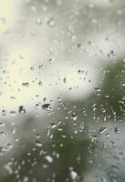 een foto van regen druppels Aan de venster glas met een wazig visie van de bloeiende groen bomen. abstract beeld tonen bewolkt en regenachtig weer voorwaarden